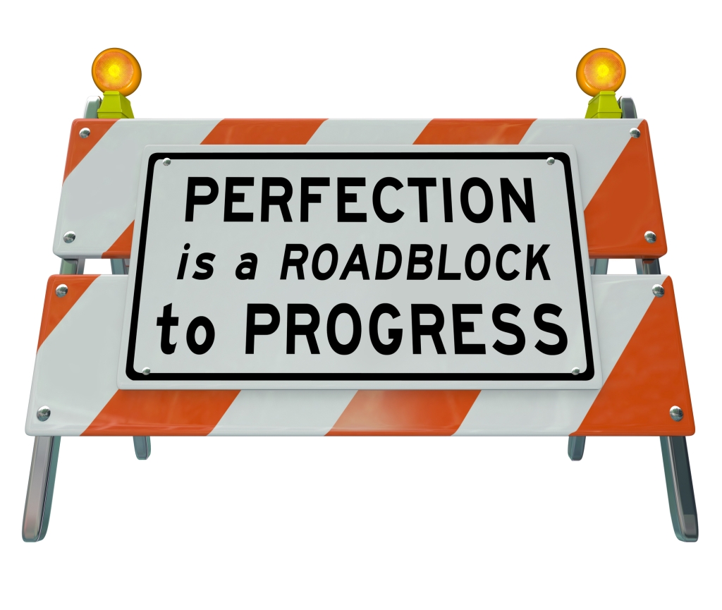 Perfection is a Roadblock to Progress words on a road construction barrier or barricade to illustrate that a drive toward perfect results can paralyze you from taking action or moving forward